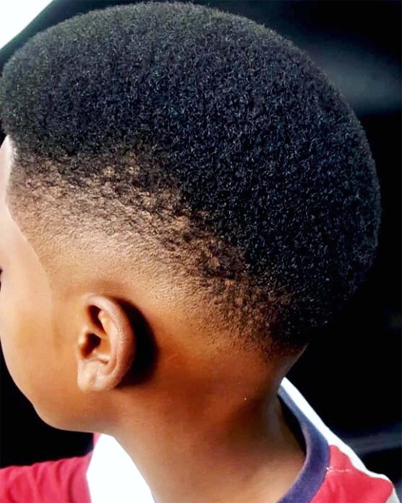 A photo of a young boy happy with his hair at a GQ Barbershop